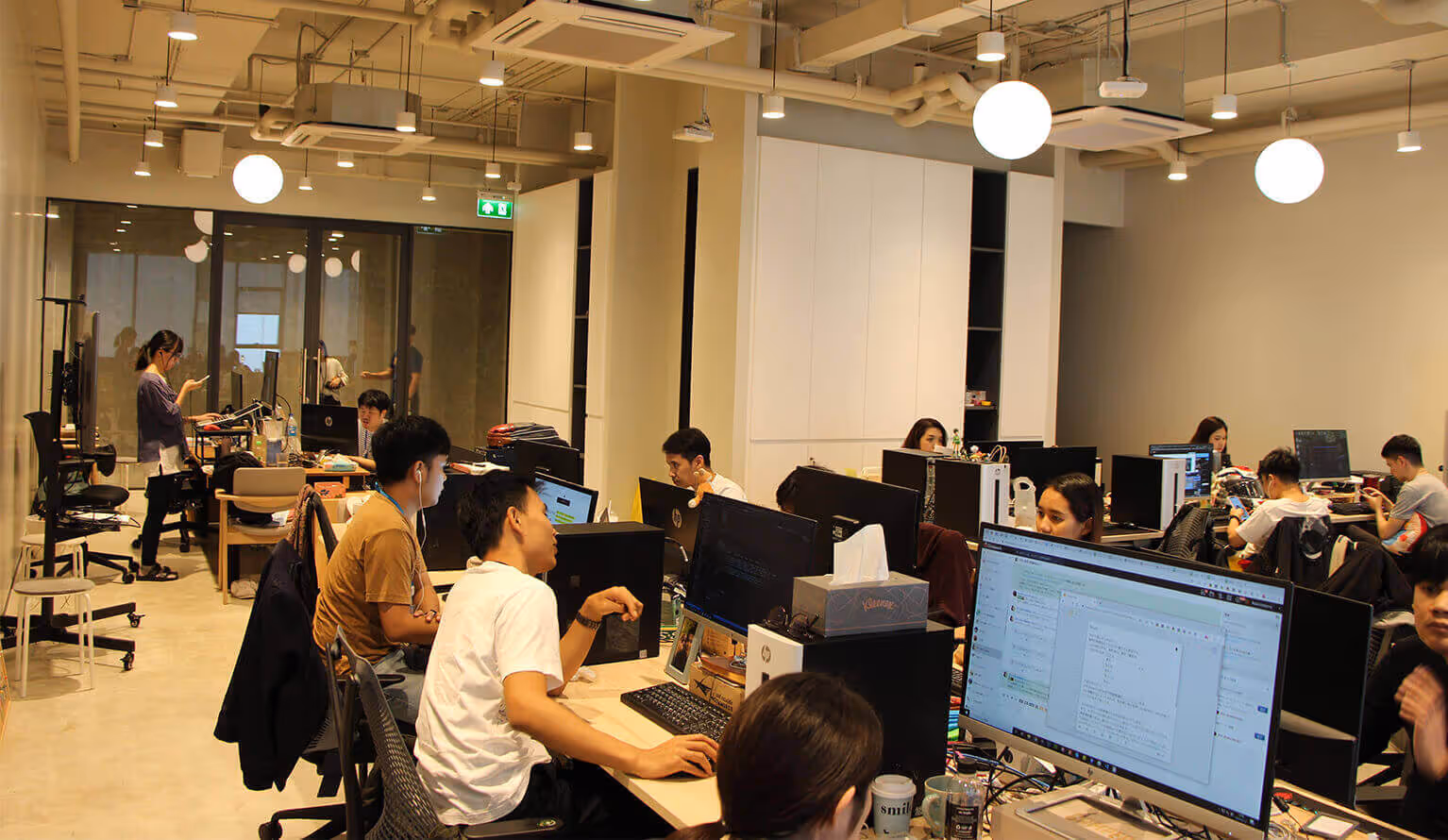 Employees working at their computers. The office space is bright and open.