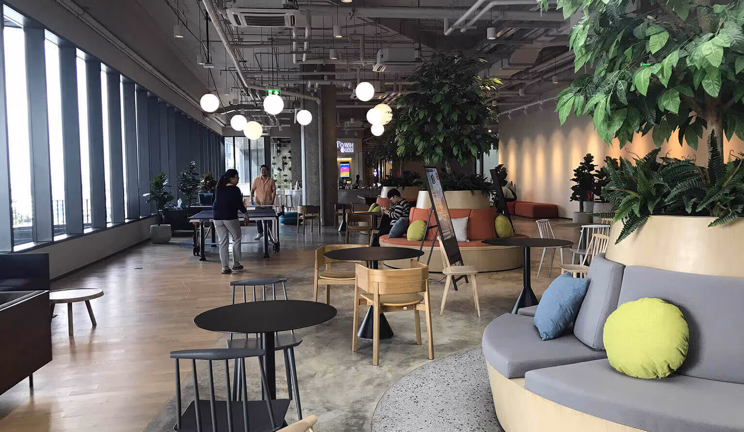 A bright and comfortable office break area surrounded by lush vegetation. It is a place where employees can relax and socialize.