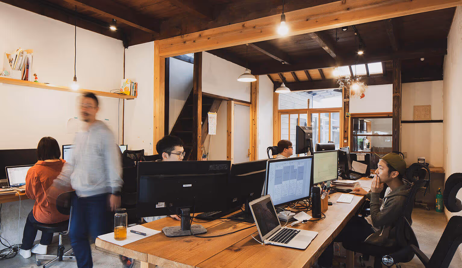 A wooden office with several employees working at computers.