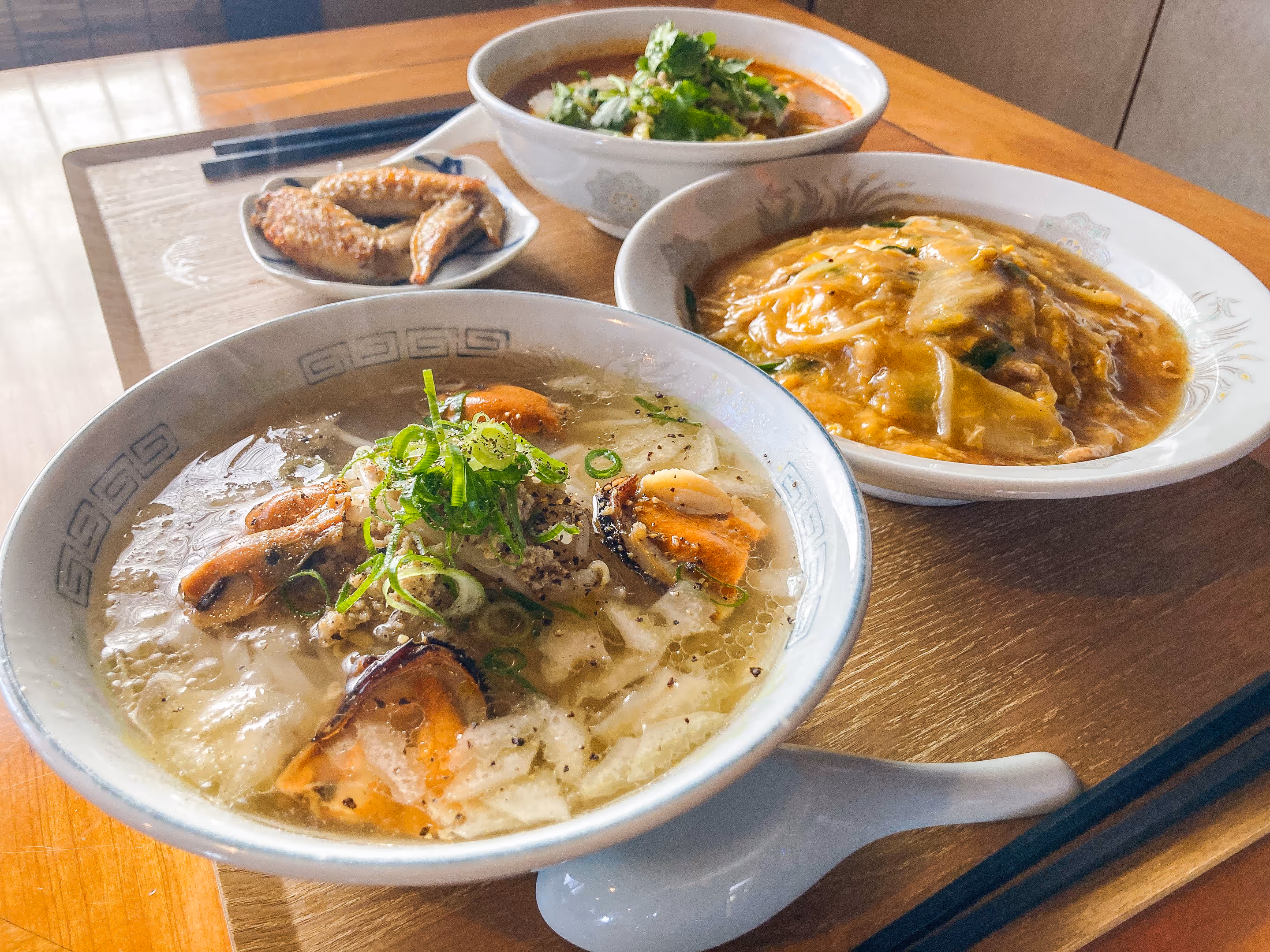 A set of Cambodian dishes on the table. Soup, stir-fried egg, chicken wings, and a small bowl of food can be seen.