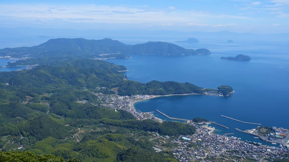 Contrast of lush green mountains and blue sea, and a superb scenic view from a hilltop.