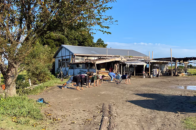 An old building on the ground with puddles. Several people are shown working on it.