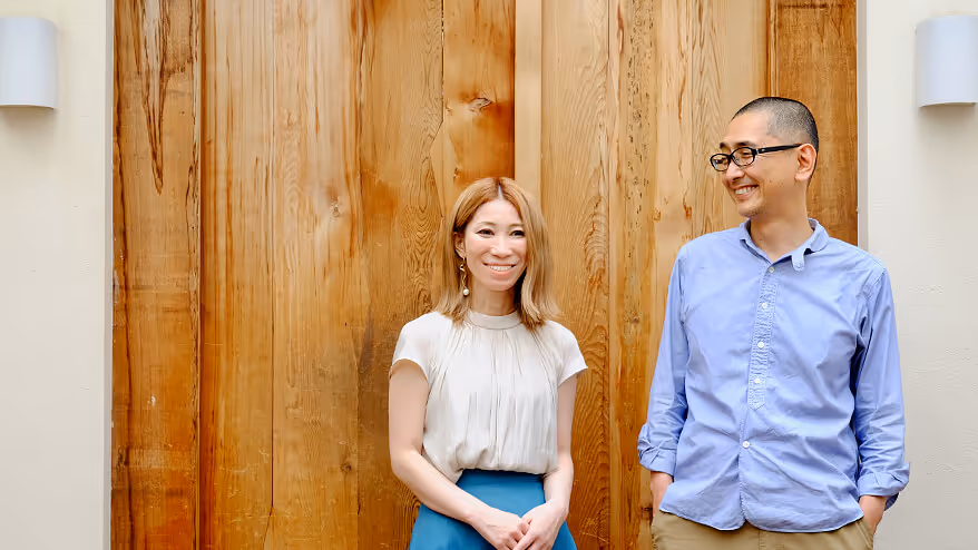 Photo of two naturally smiling men and two women standing against a wooden wall.