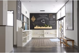 Bright salon room with blackboard walls and white shelves.