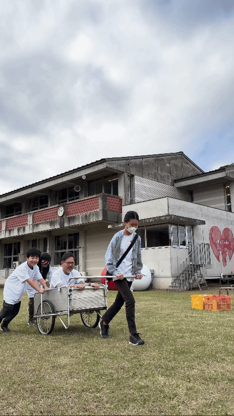 Children vigorously pulling a cart carrying an adult