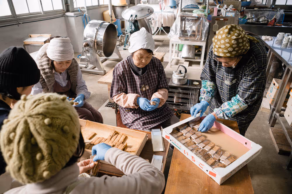 In the workshop, women are carefully packing KAMIYAMA MATEwith gloves on.