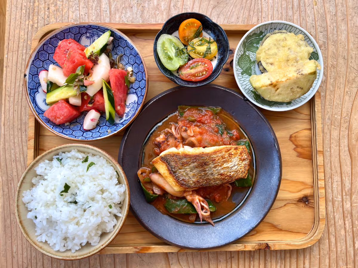 Served on wooden trays, this lunch makes the most of freshly picked regional ingredients. A variety of dishes, including white rice, seafood stewed in tomato sauce, and watermelon salad, are beautifully presented.
